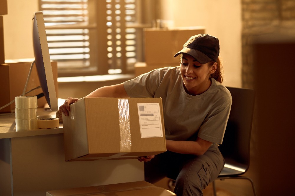 happy-delivery-woman-preparing-cardboard-boxes-dispatch-while-working-office.jpg