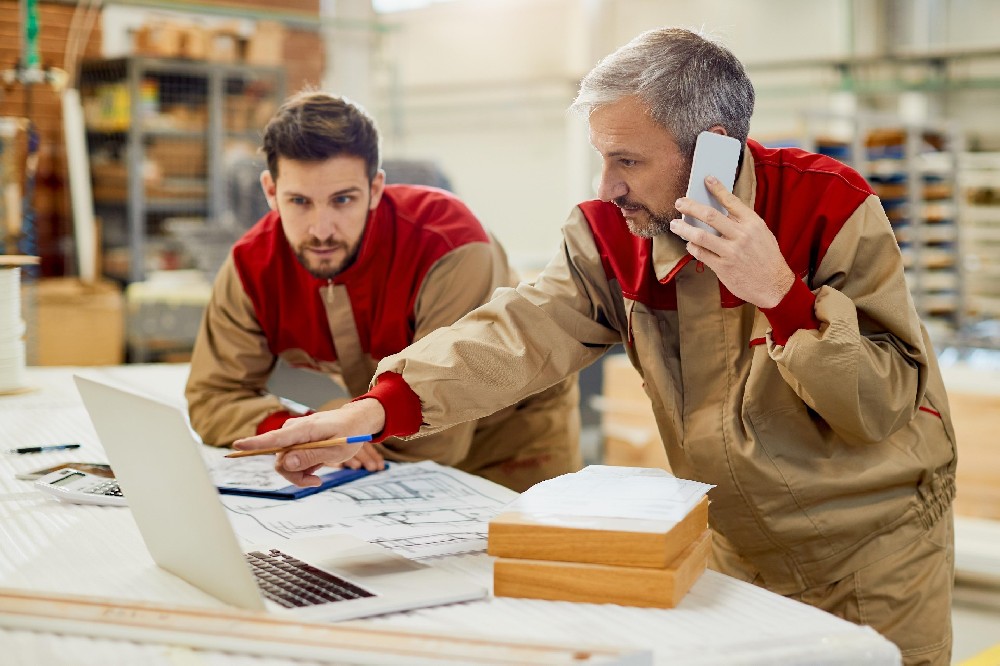 carpenter-talking-phone-while-using-computer-workshop.jpg